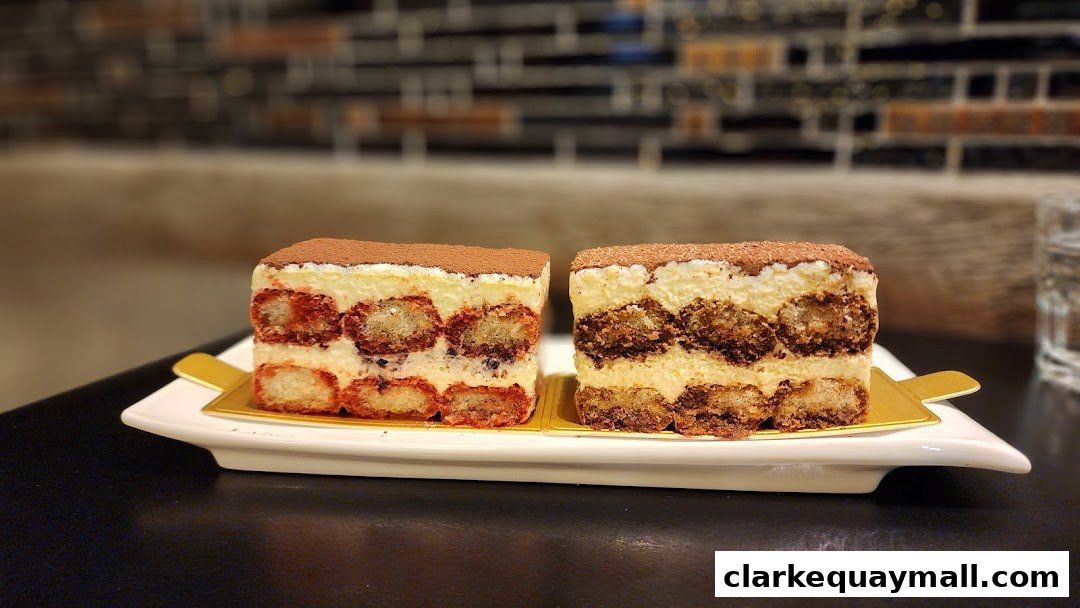 Two slices of tiramisu cake are presented on a white plate with a blurred background.