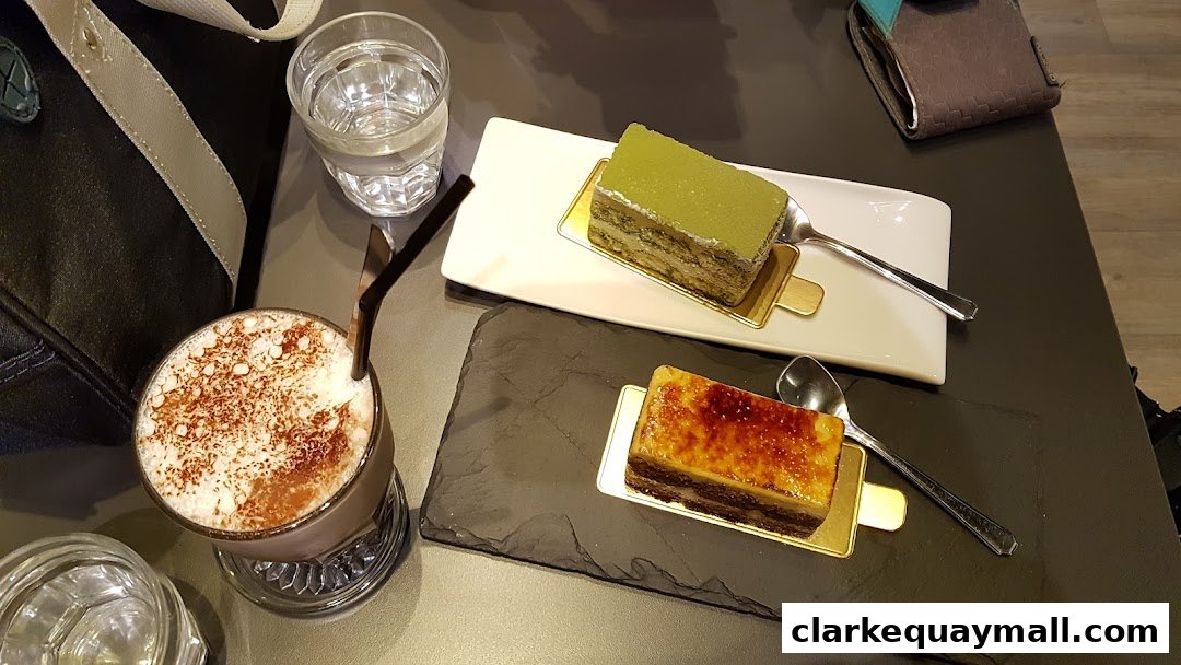 A table setting with two slices of cake, a drink, and a glass of water.