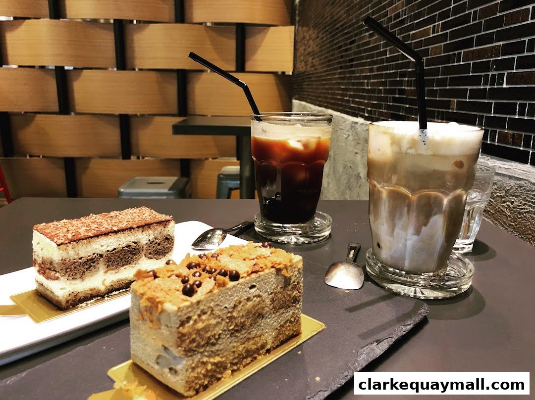 Two slices of tiramisu cake and two iced coffee drinks on a table.