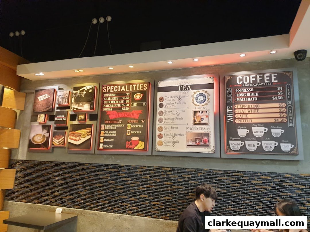 A wall display featuring menus for coffee, tea, and specialities at L'Atelier Tiramisu.