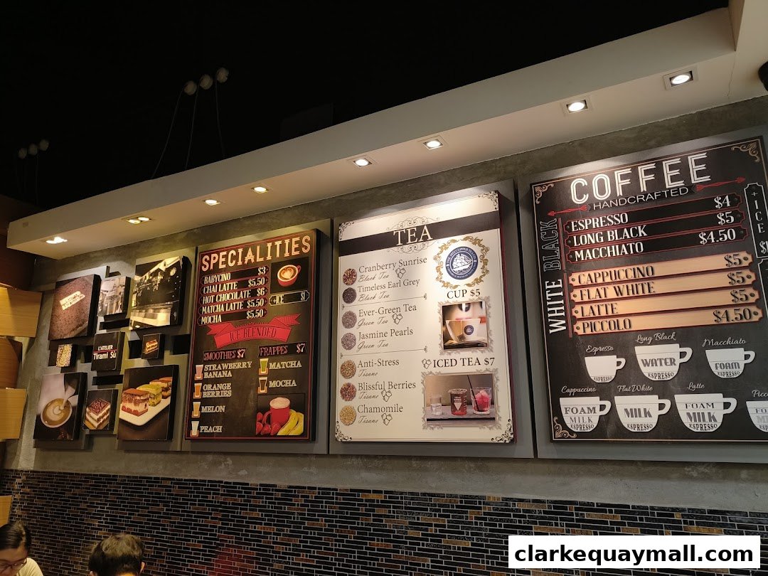 A menu board displaying coffee, tea, and specialty drinks with prices.