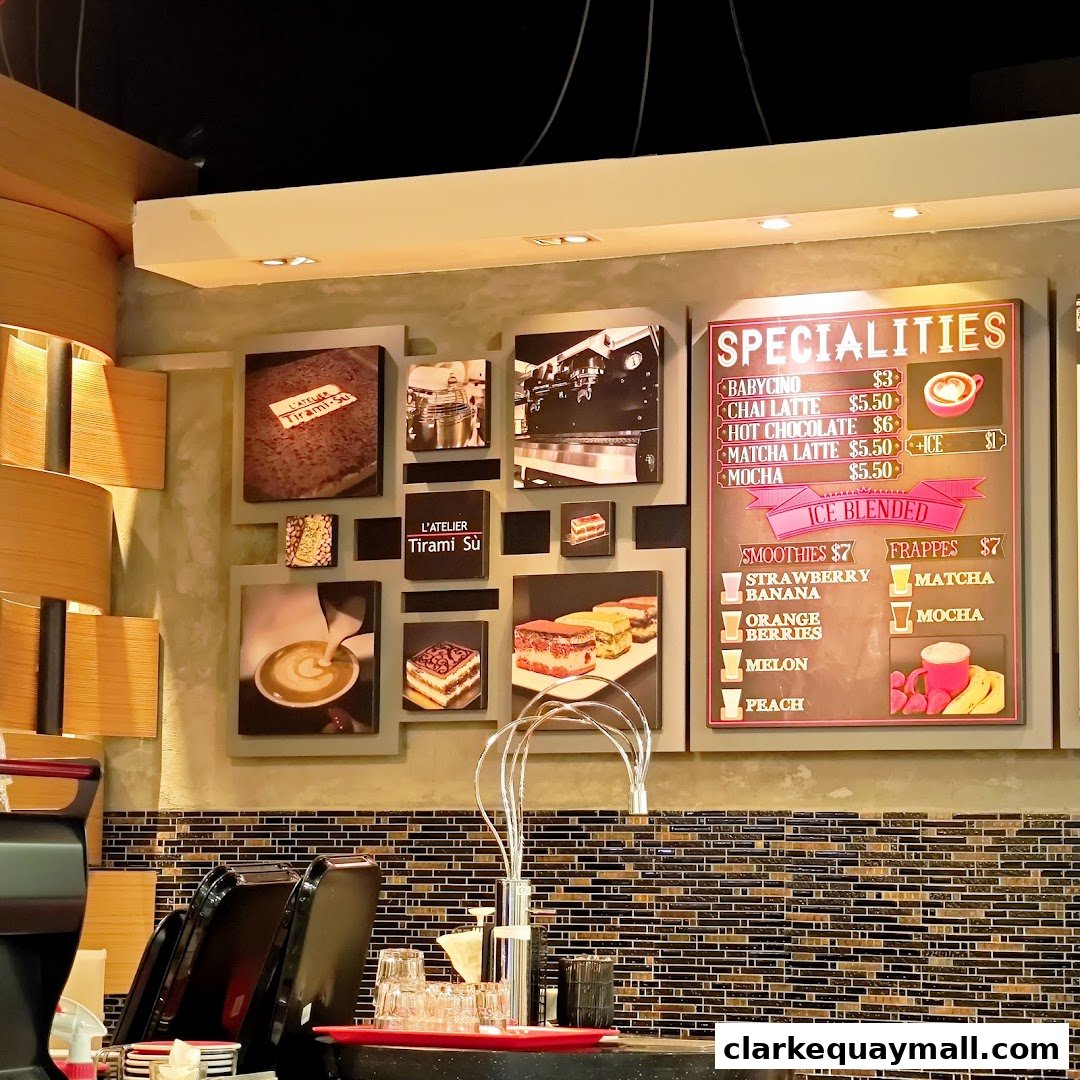 A wall display at L'Atelier Tiramisu featuring photos of desserts and a menu board.