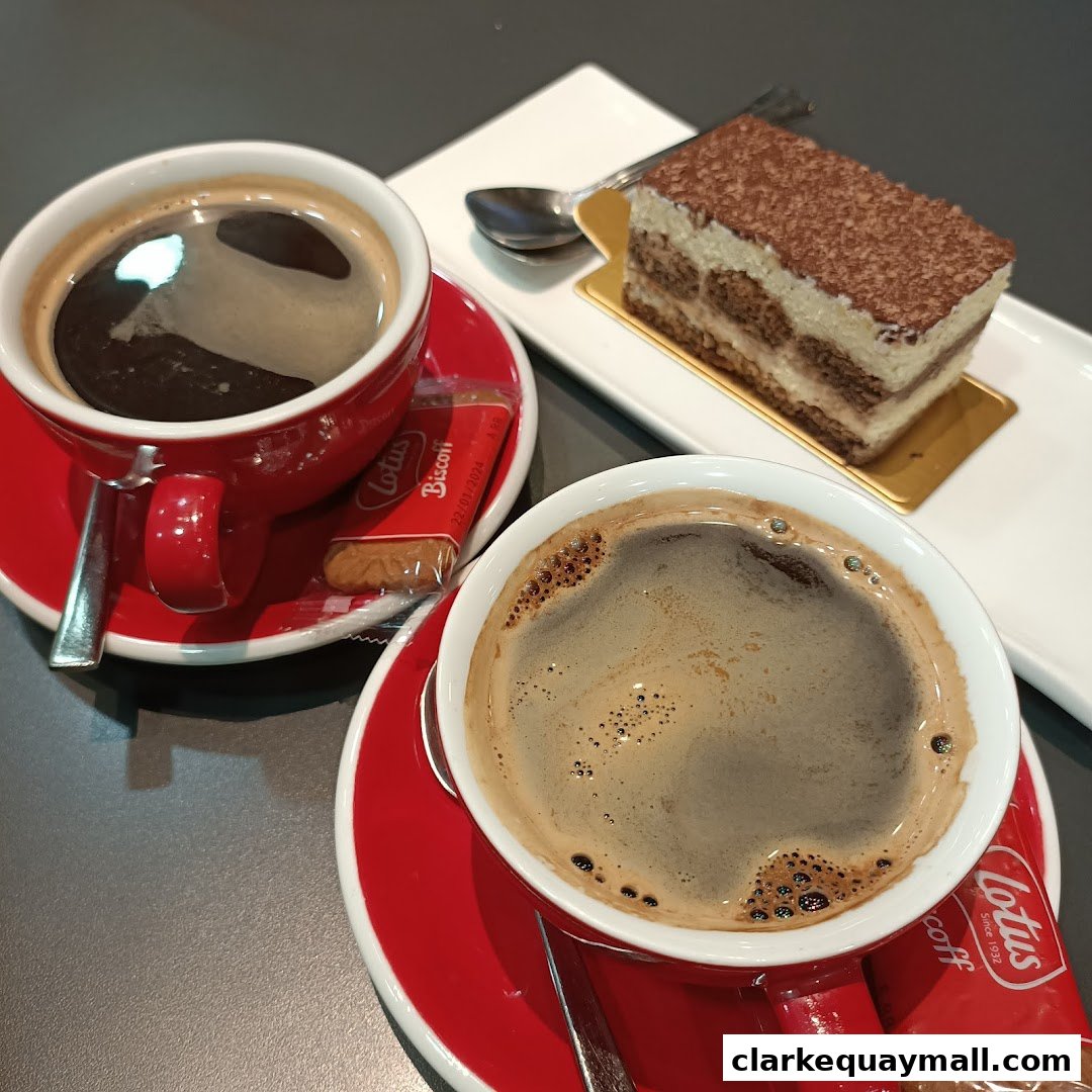 Two cups of coffee and a slice of tiramisu cake on a table.