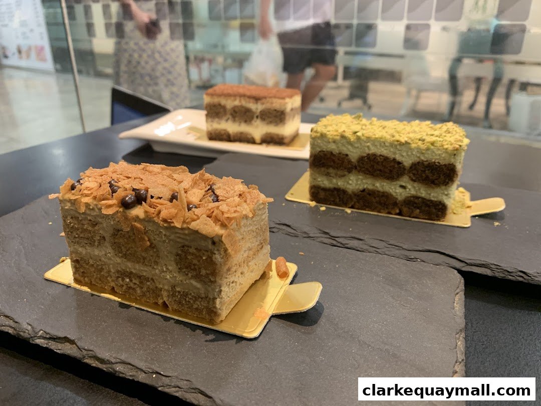 Three delicious tiramisu desserts are displayed on a dark surface.