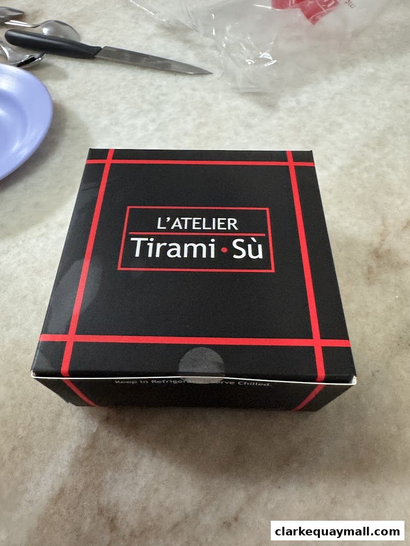 A black box with red trim and the shop name L'Atelier Tiramisù is displayed.