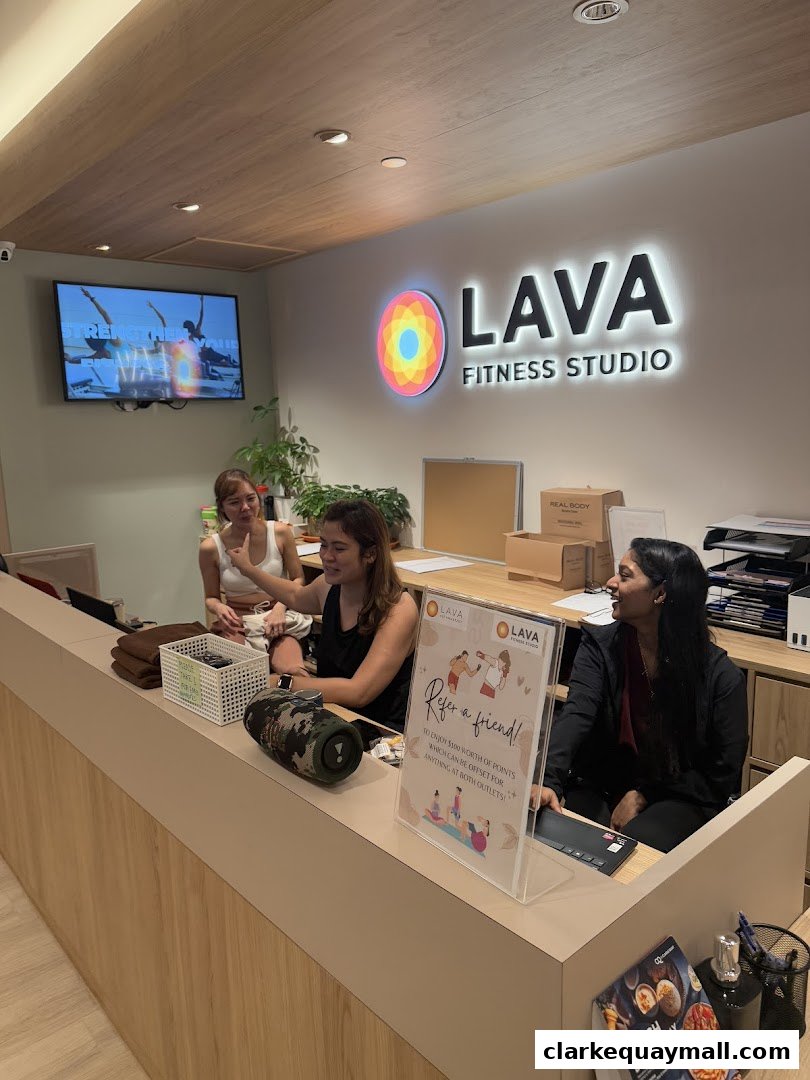 Staff members at the reception desk of LAVA Fitness Studio, with branding and promotional materials visible.
