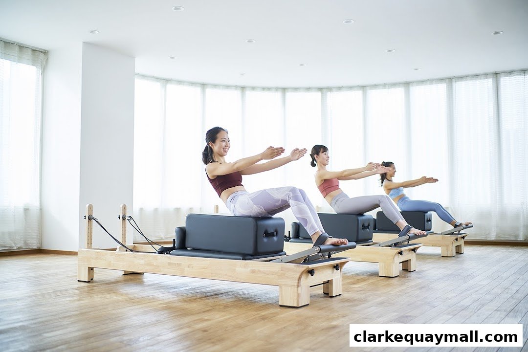 Three women are performing a Pilates exercise on reformers in a bright, airy studio.