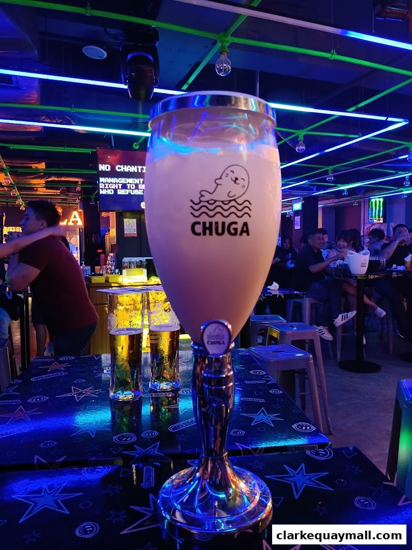 A large drink with a seal logo sits on a table in a bar with neon lights.