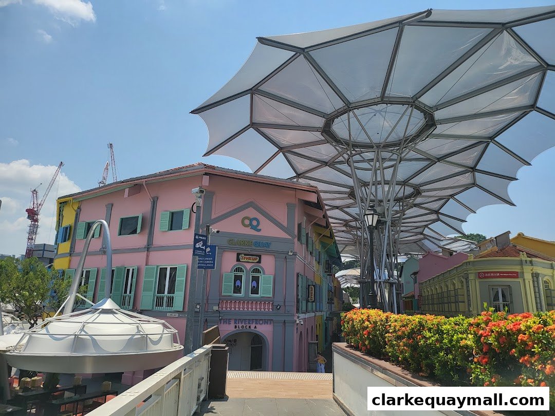 Colorful buildings and a modern canopy structure at Clarke Quay on a sunny day.