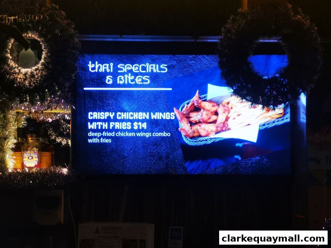 A digital menu board displays Thai specials and crispy chicken wings with fries.