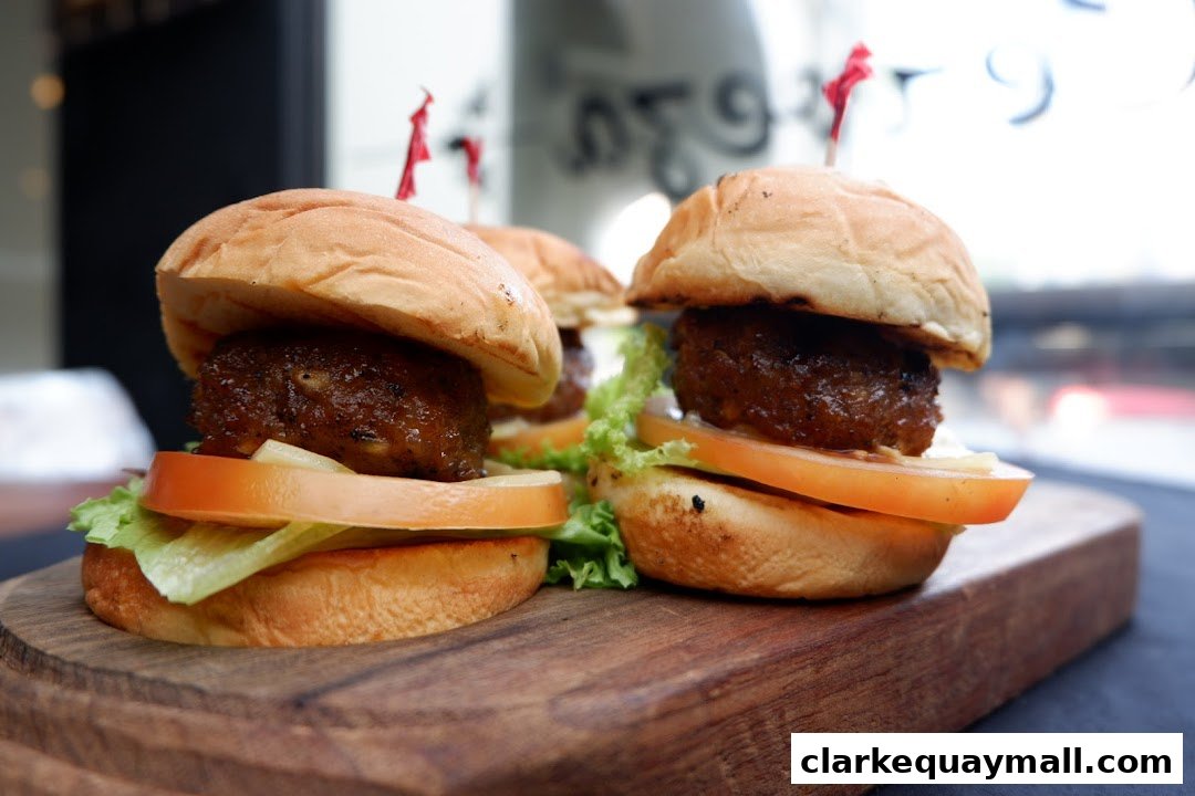 Three delicious mini burgers with lettuce and tomato served on a wooden board.