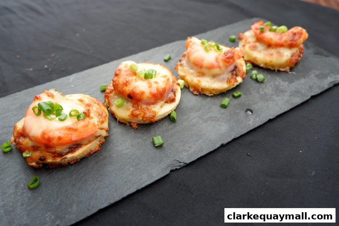 Four delicious shrimp and cheese appetizers topped with green onions on a slate platter.