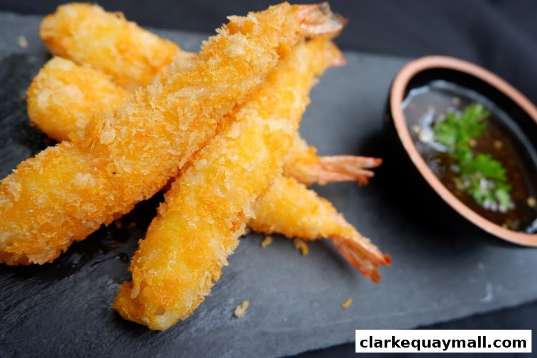 Crispy fried shrimp served with a dipping sauce on a dark slate.