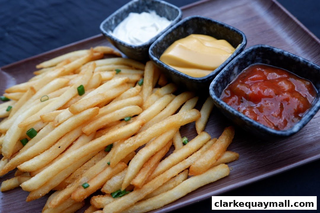 A close-up shot of crispy french fries served with three dipping sauces: ketchup, cheese sauce, and a white sauce.