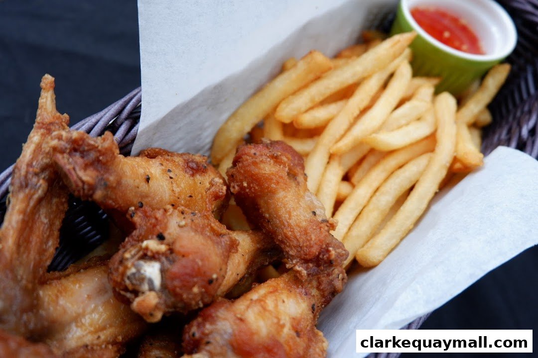 A basket filled with crispy fried chicken wings and golden french fries, served with a side of dipping sauce.