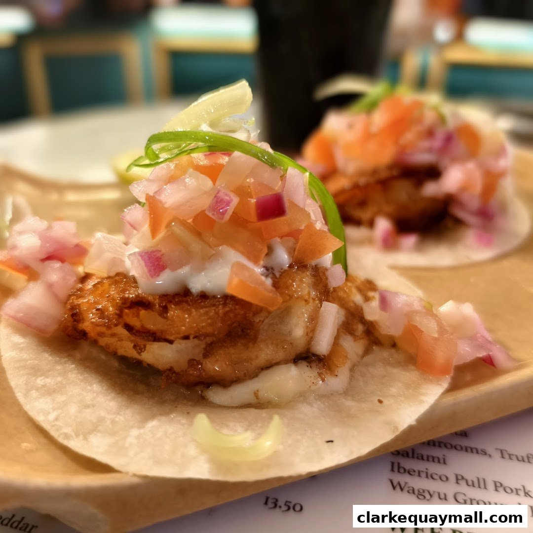 Close-up of two delicious tacos topped with fresh salsa and a creamy sauce.