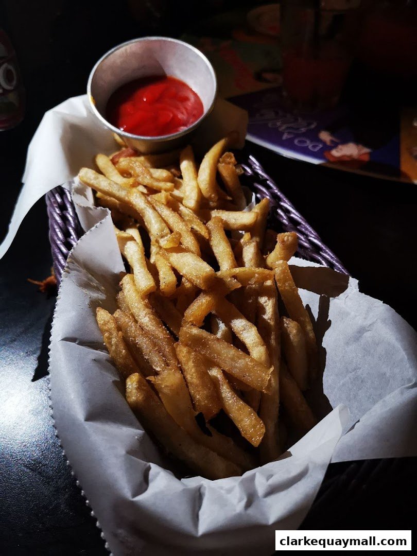 A basket of golden french fries served with a side of ketchup.