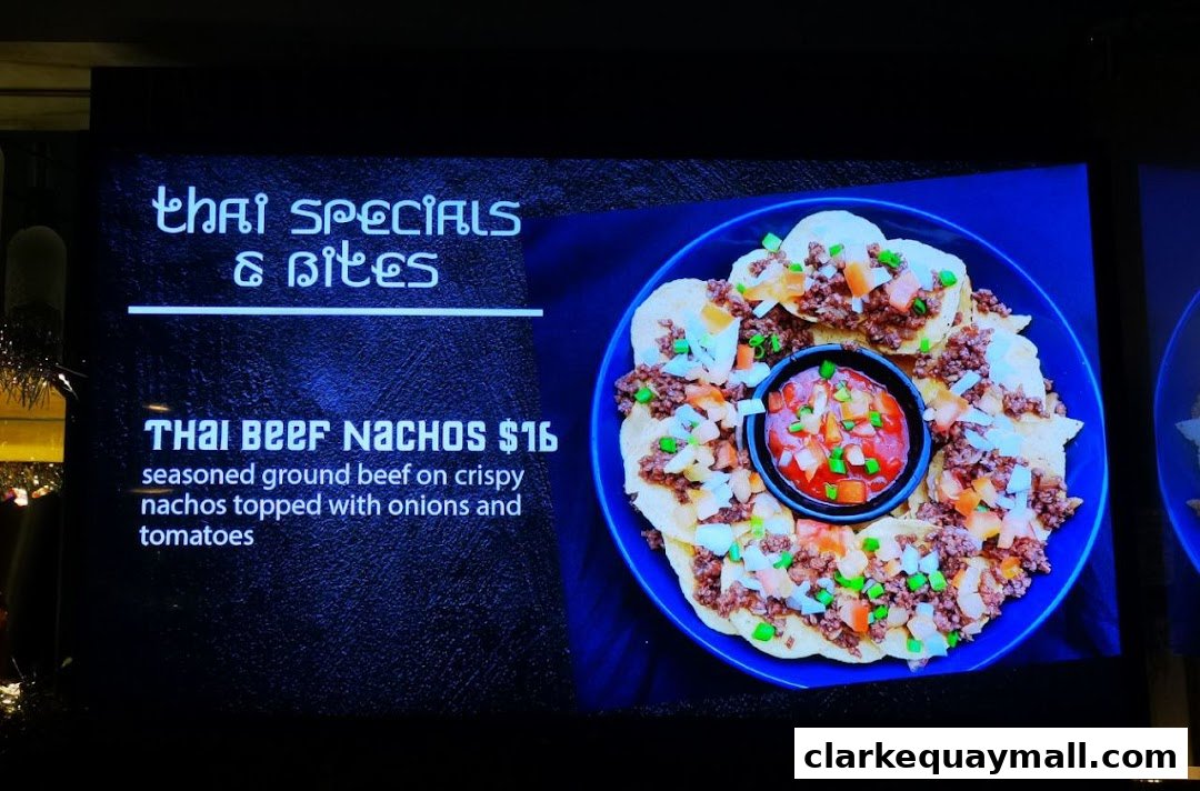 A digital menu board displaying Thai Beef Nachos with a description and price.