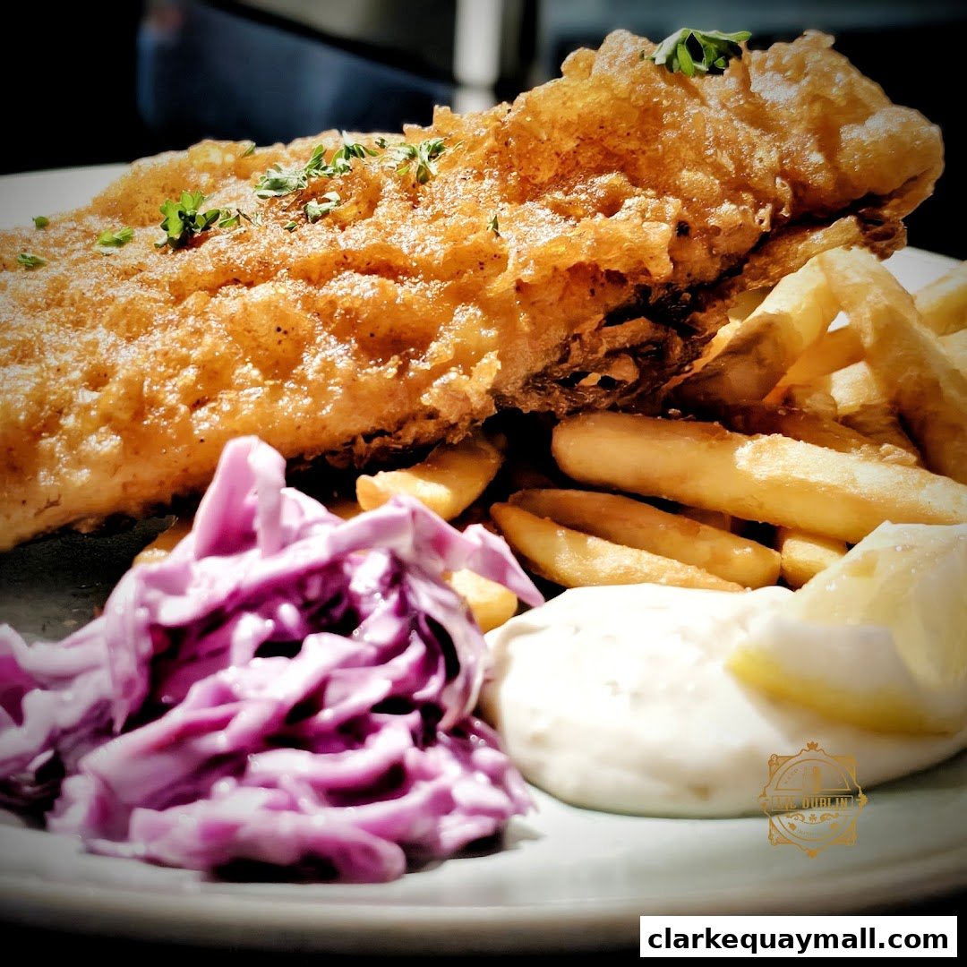 A close-up of a delicious fish and chips meal with coleslaw and tartar sauce.
