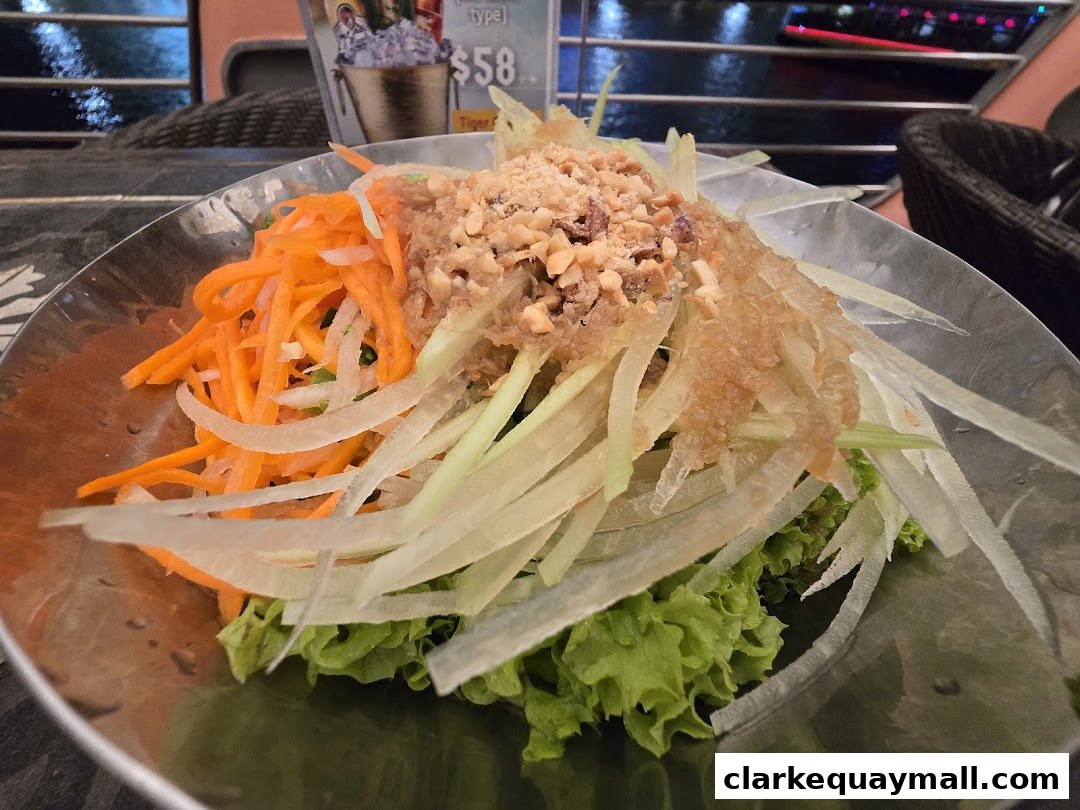 A close-up of a fresh salad with shredded carrots, green papaya, and peanuts.