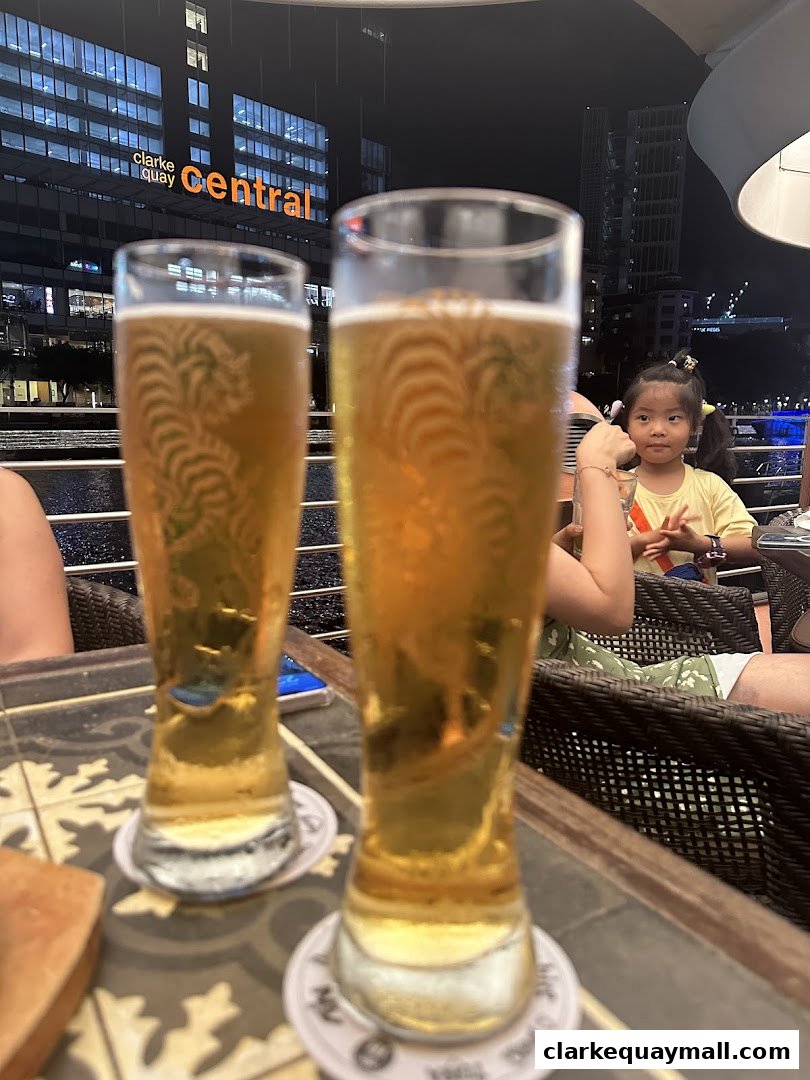 Two glasses of beer on a table with a child and city lights in the background.