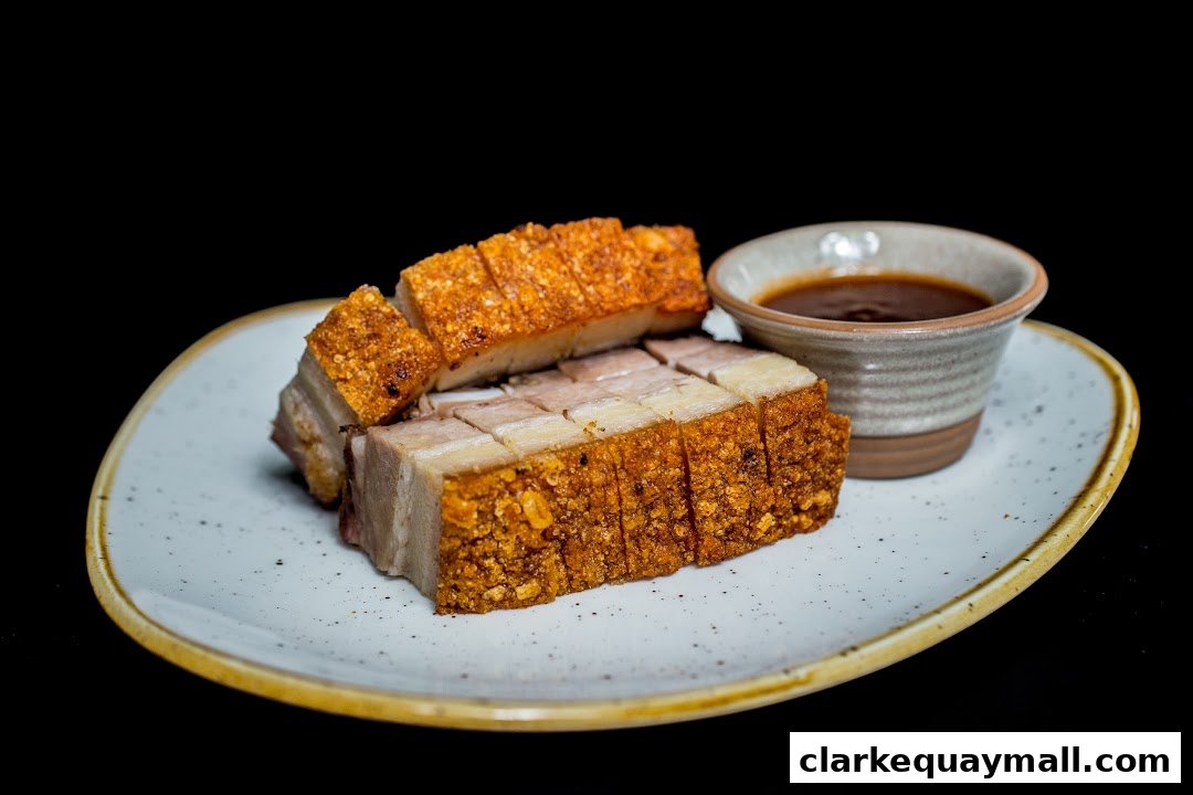 Crispy roasted pork belly served with a dipping sauce on a speckled plate.