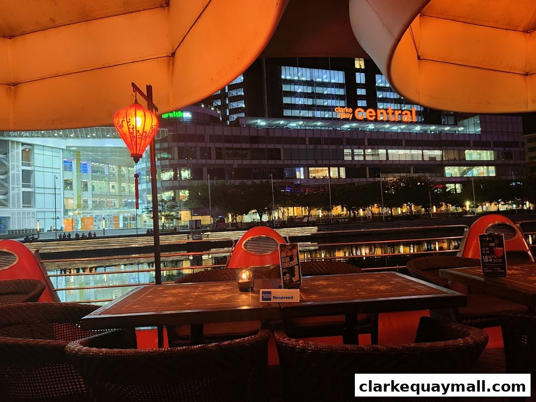 Outdoor seating area at night with a view of Clarke Quay Central.