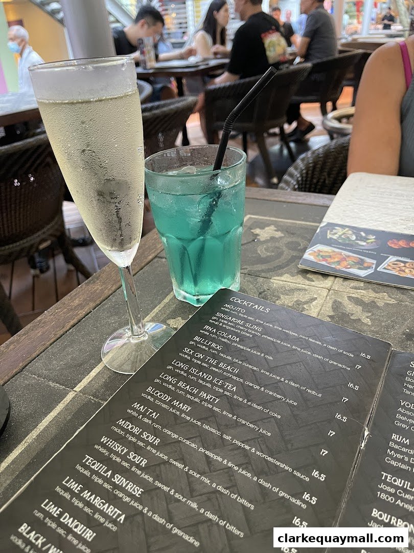 A close-up of two drinks on a table with an open menu displaying cocktails.