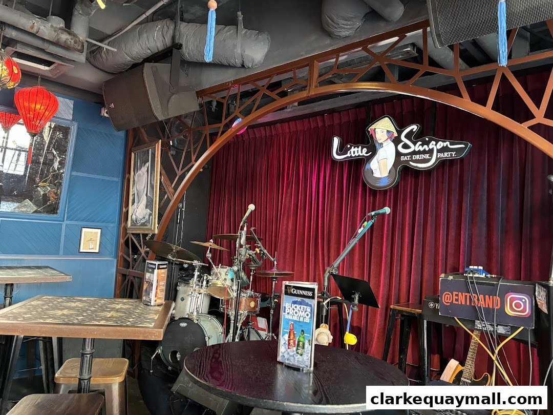 Interior of Little Saigon with a stage, drum set, and seating.
