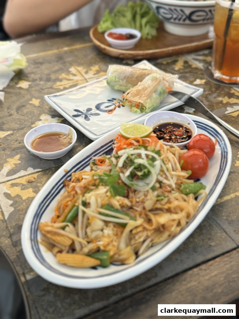 A close-up of a delicious Vietnamese noodle dish with spring rolls and dipping sauce.