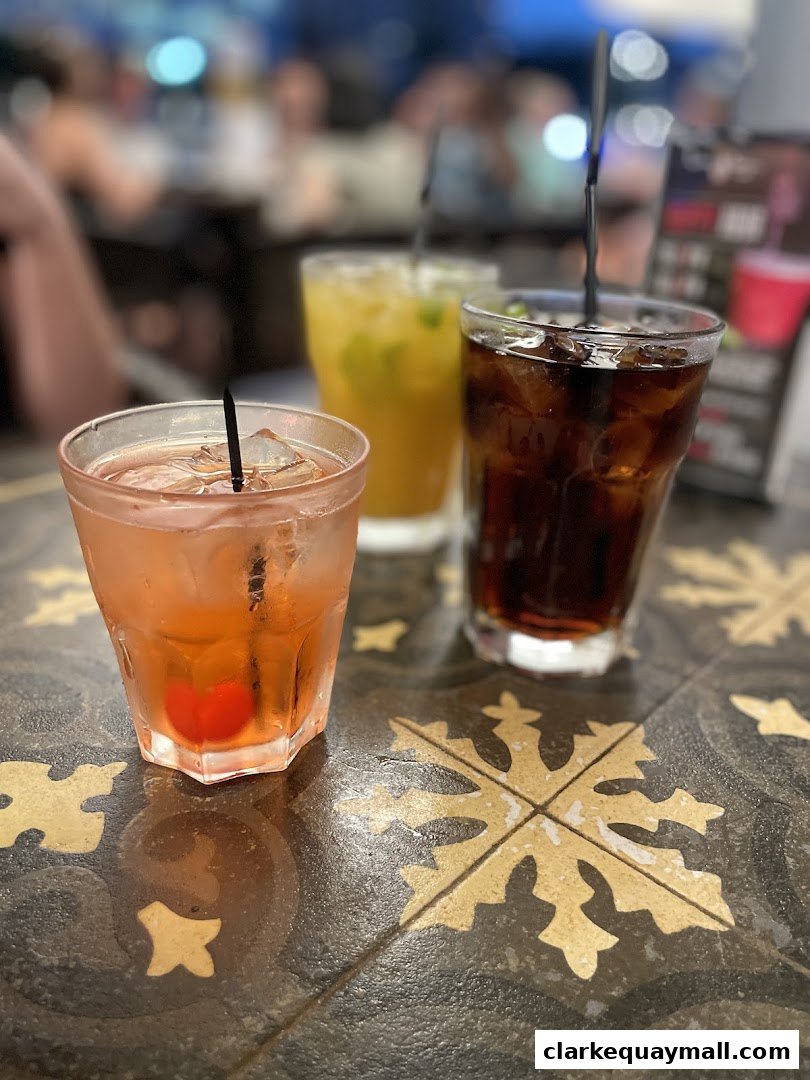 Three refreshing drinks with ice and garnishes on a patterned table at Little Saigon.