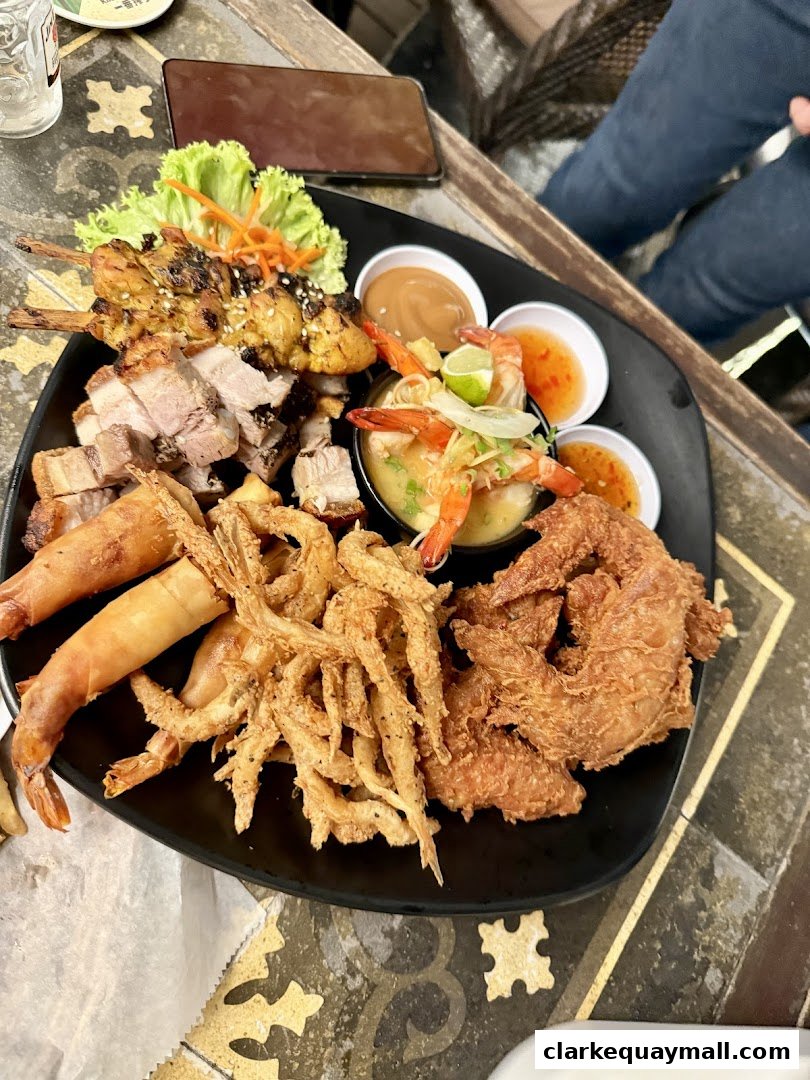A platter of assorted Vietnamese appetizers including spring rolls, fried shrimp, chicken skewers, and crispy pork belly.
