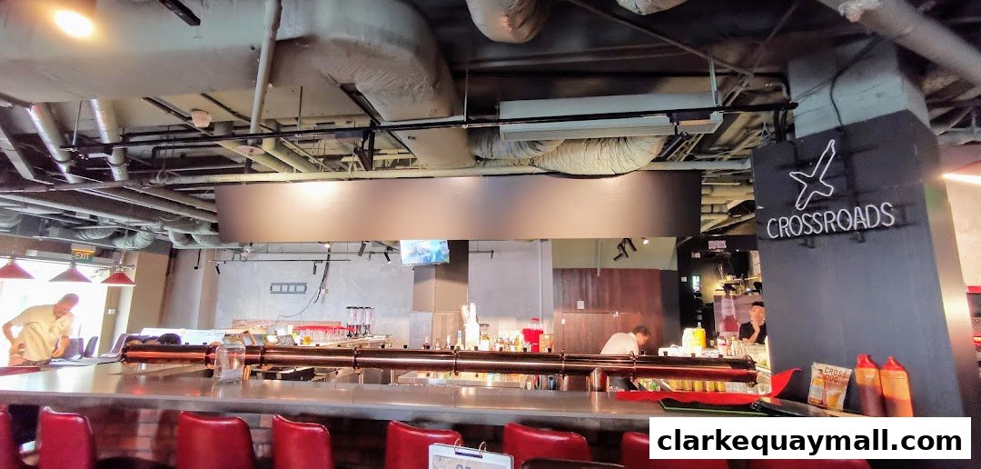 Interior of a bar with red stools, a long counter, and neon signage.