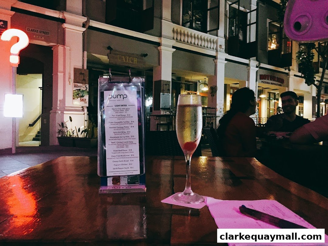 A table at a restaurant with a champagne flute and a menu, with people dining in the background.