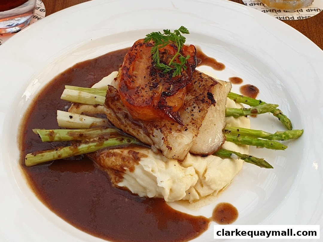 A gourmet dish featuring pan-seared fish, mashed potatoes, asparagus, and a rich sauce.