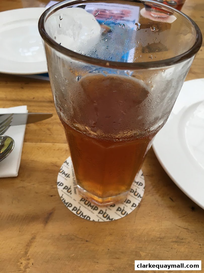 A close-up of a glass of iced tea on a wooden table with a coaster.