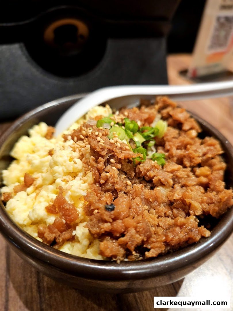 A close-up of a bowl of ramen with scrambled eggs and minced pork.