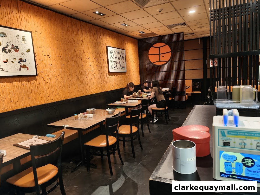 Interior view of Marutama Ramen The Central with tables, chairs, and decor.