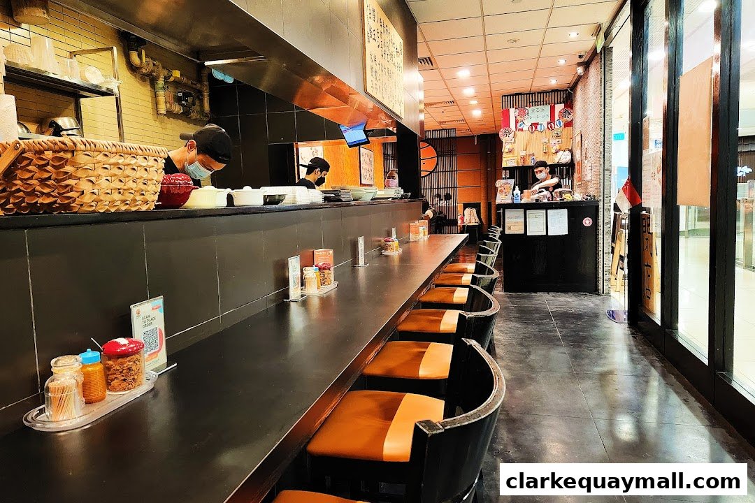 Interior view of Marutama Ramen showing a long counter with empty seats and staff preparing food.