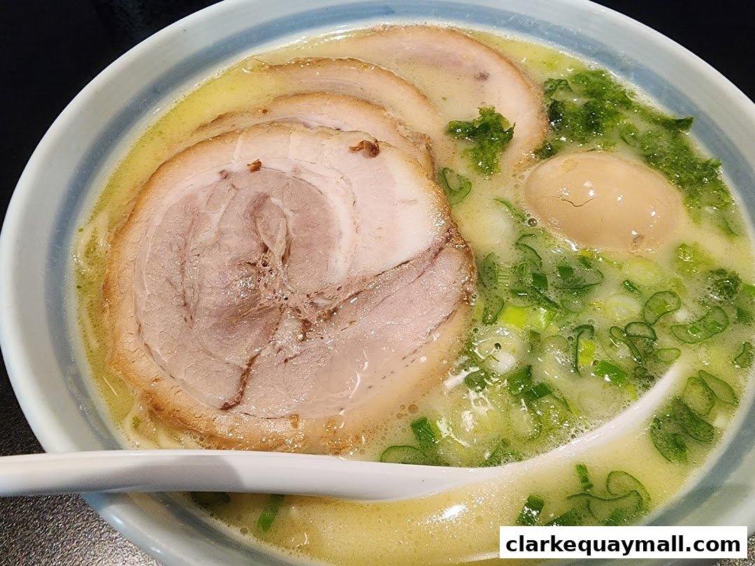 A close-up of a delicious bowl of ramen with chashu pork, egg, and green onions.