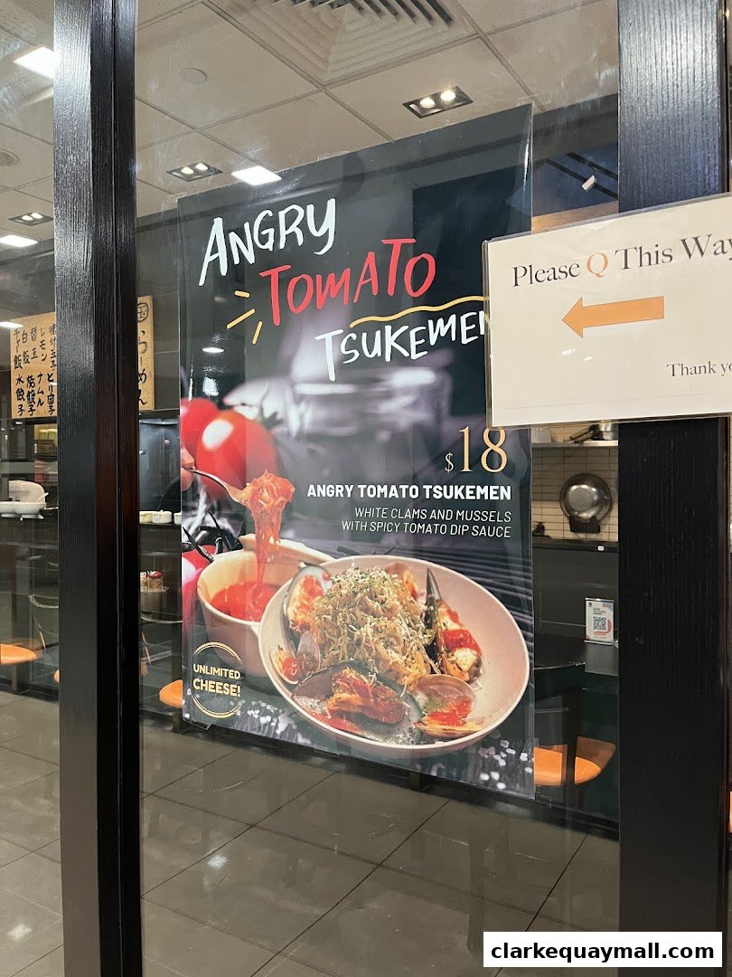 A poster for Angry Tomato Tsukemen ramen with clams and mussels is displayed in a shop window.