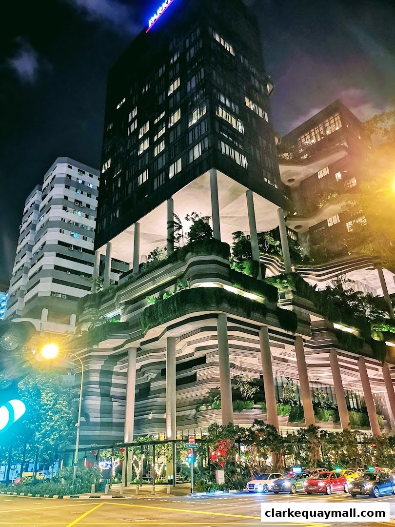 A modern building with unique layered architecture and greenery at night.