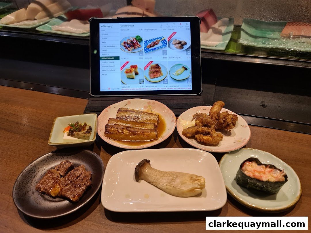 A selection of Japanese dishes and a tablet displaying a menu at Mitsuba Japanese Restaurant.
