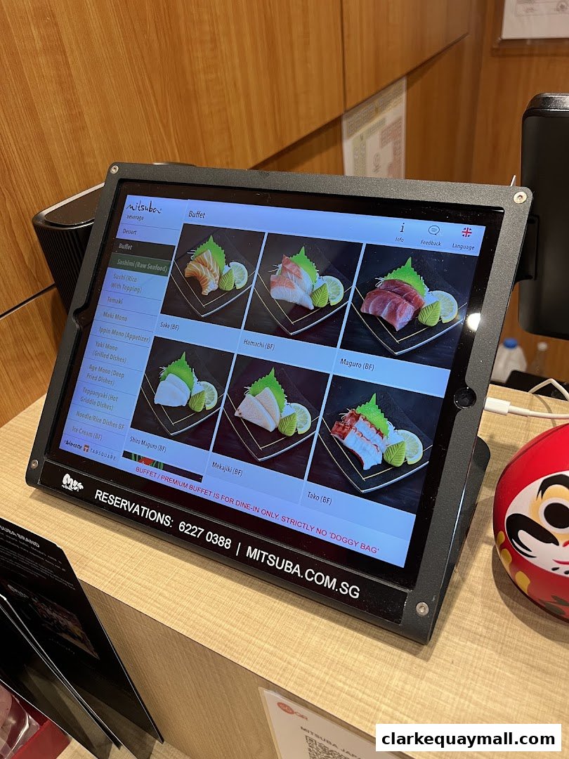 A digital menu displaying various Japanese dishes, primarily sashimi, at Mitsuba Japanese Restaurant.