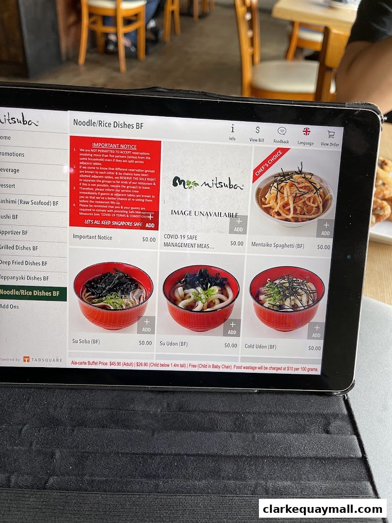 A tablet displays the menu for Mitsuba Japanese Restaurant, featuring noodle dishes.