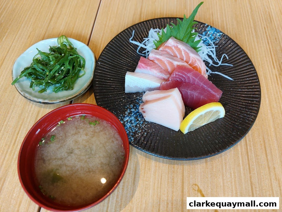 A plate of assorted sashimi, a side of seaweed salad, and a bowl of miso soup.