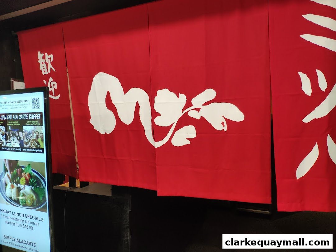 Red Japanese noren curtains with white calligraphy and a digital menu board.