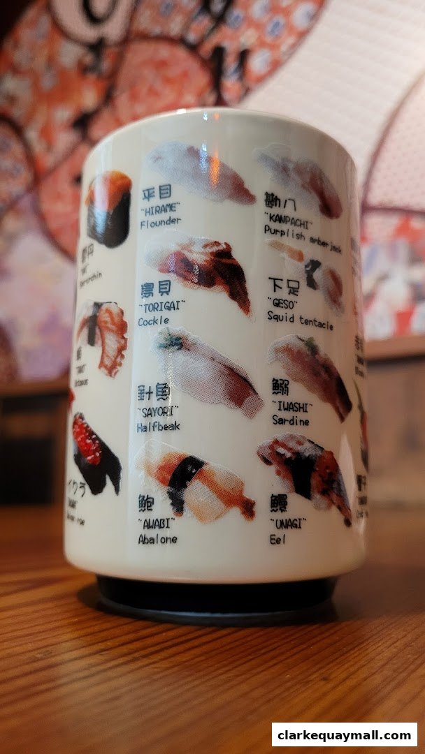 A ceramic cup with illustrations and names of various sushi dishes.