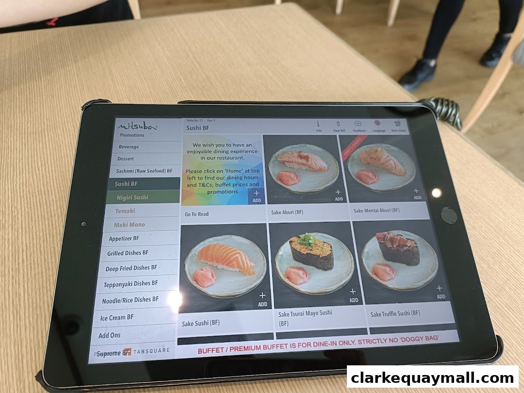A tablet displays a digital menu for Mitsuba Japanese Restaurant, showcasing sushi items.