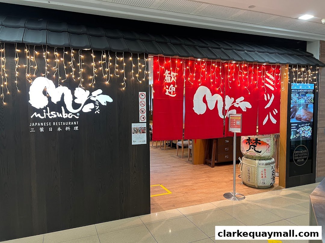 The exterior of Mitsuba Japanese Restaurant with a dark wood facade and red Noren curtains.